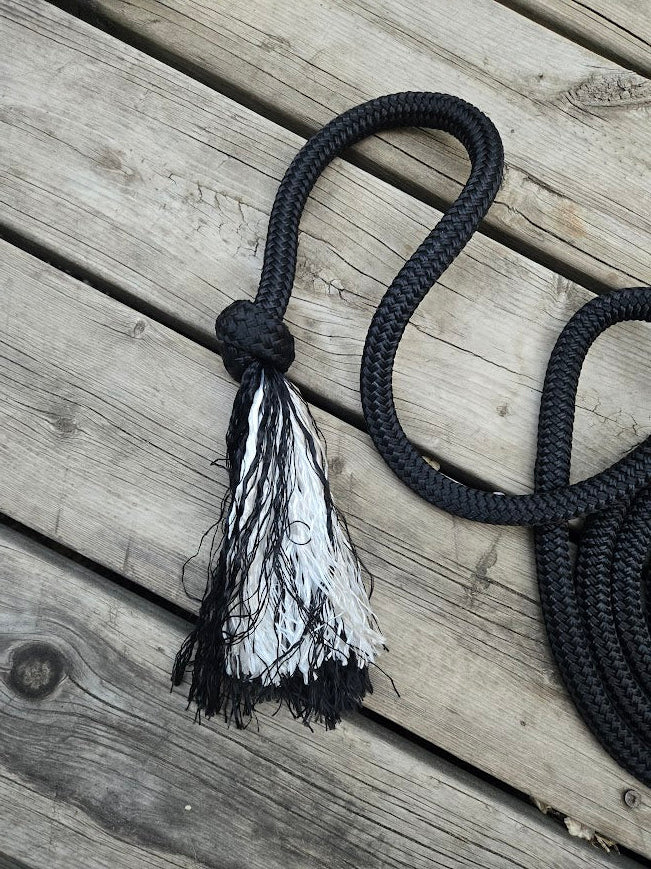 Black rope with a feathered end on a wooden surface