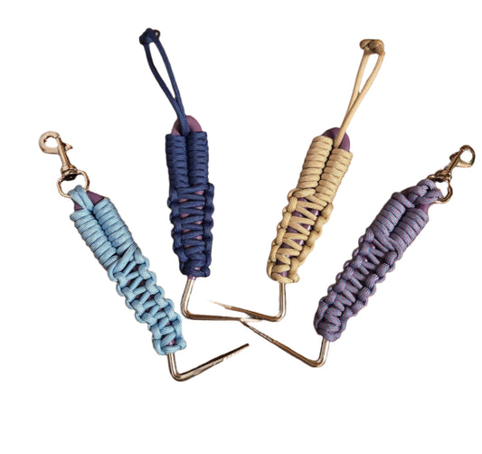 Four hoof picks with braided paracord , designed to attach to English or Western saddles. Comes in light blue, navy, cream, and lavender.